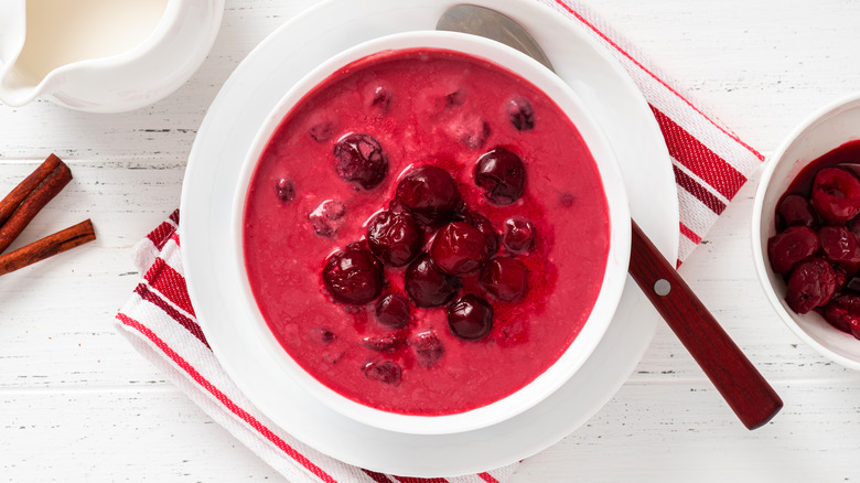 White bowl of red soup with whole cherries