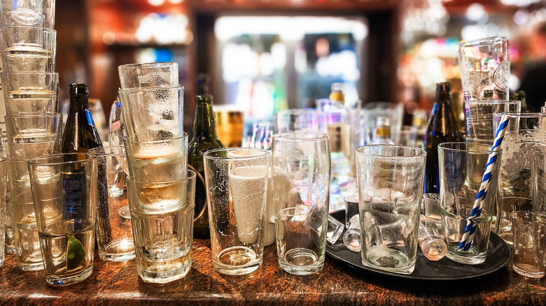 Empty bottles and shot glasses stacked across bar countertop