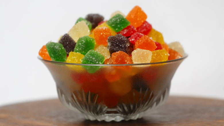 Colorful tutti frutti pieces in a glass bowl on a wooden table