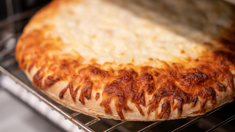 A cheese toaster pizza on a wire rack, cooked.