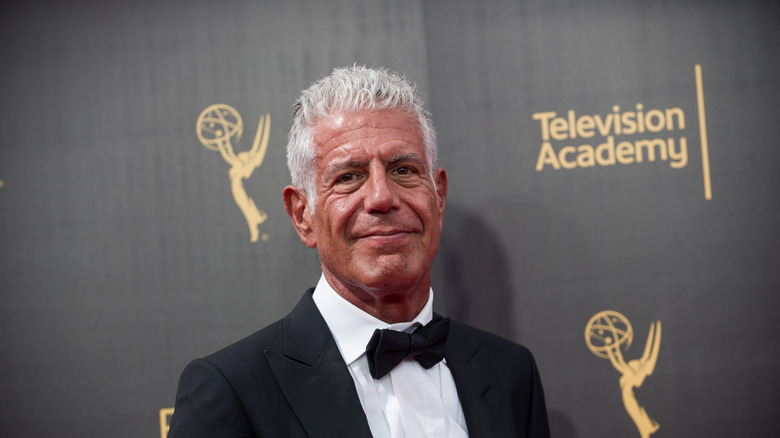 Anthony Bourdain standing in front of a red carpet backdrop for the Television Academy.