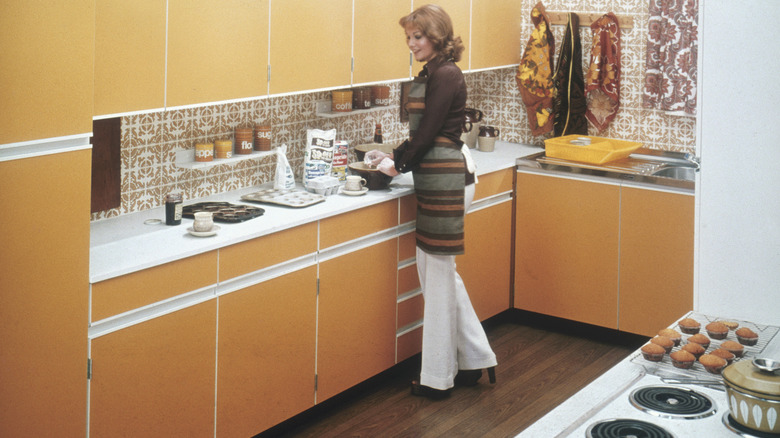 Woman standing in a retro, 1970s style kitchen