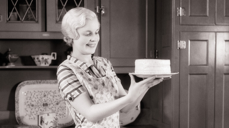 black and white photograph of a woman holding a cake