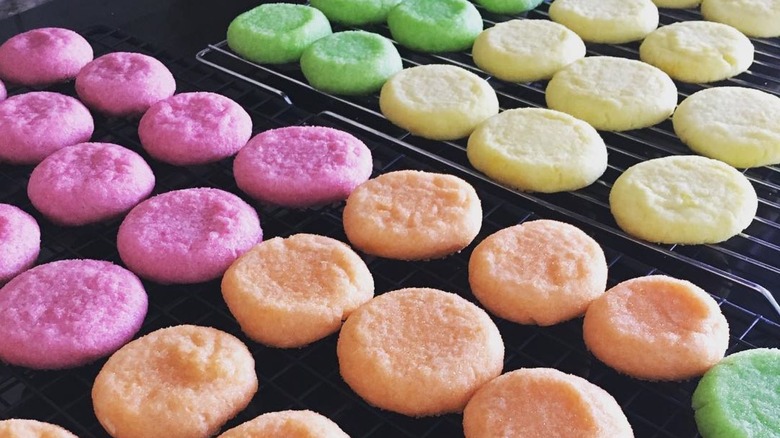 Pink, orange, yellow, and green sugar cookies on cooling racks