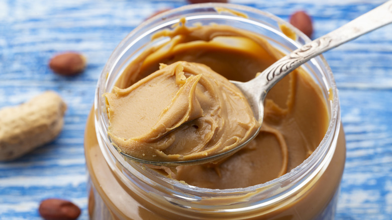 A spoonful of peanut butter being removed from a jar