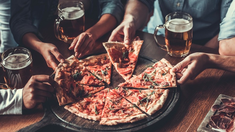 People with pizza and beer on table in a pizza parlor