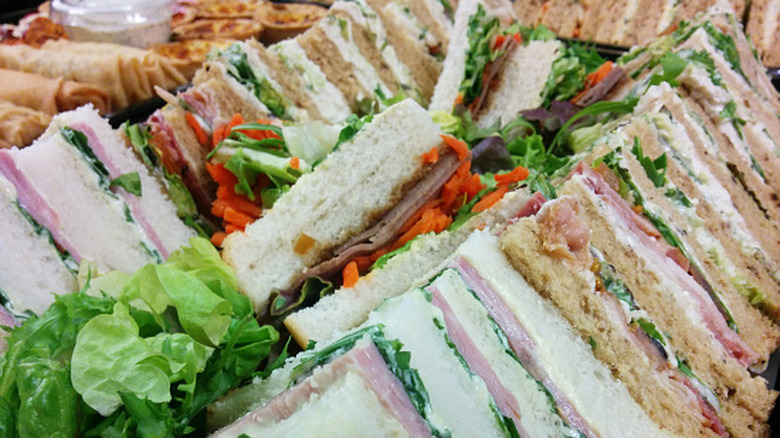 A tray of assorted sandwiches cut into triangular quarters