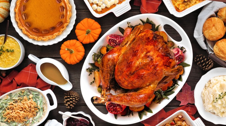 Various Thanksgiving foods and harvest decorations on a wooden table