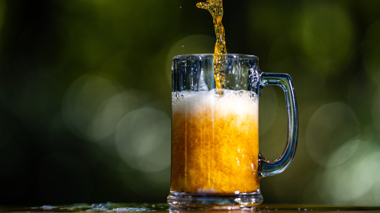 Golden craft beer being poured into cup outdoors