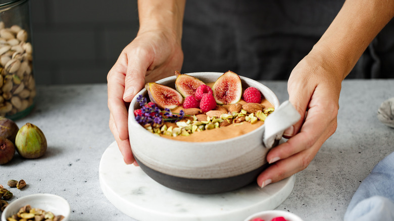 A bowl of whole foods including berries, figs, and nuts.