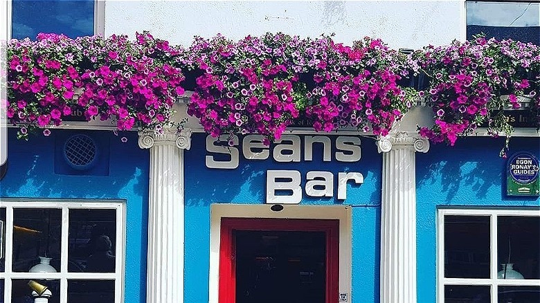 The exterior of Sean's Bar, with imitation classical pillars flanking the door and purple flowers hanging down