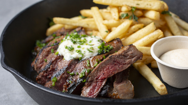 Steak served with fries, mayonnaise, and a chive topping