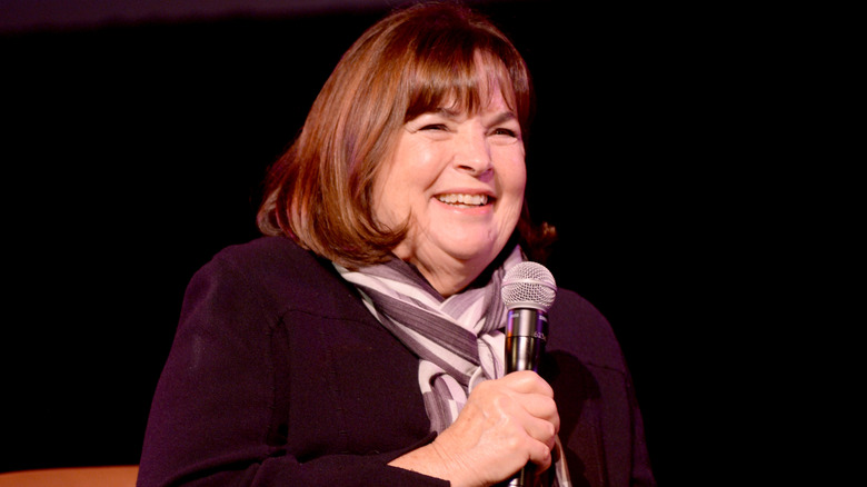 Ina Garten laughs at an event with microphone in hand