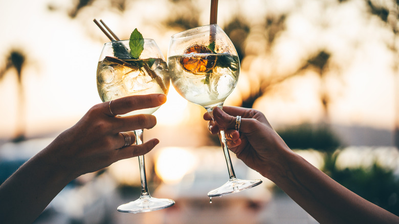 Two people clinking wine glasses with cocktails in them outside