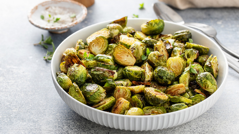 Crispy roasted or air fried brussel sprouts with honey dressing served in a white bowl.