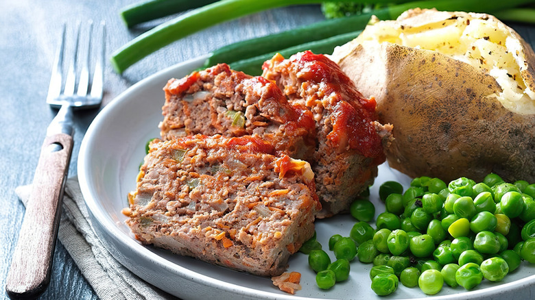 Sliced meatloaf with baked potato and peas