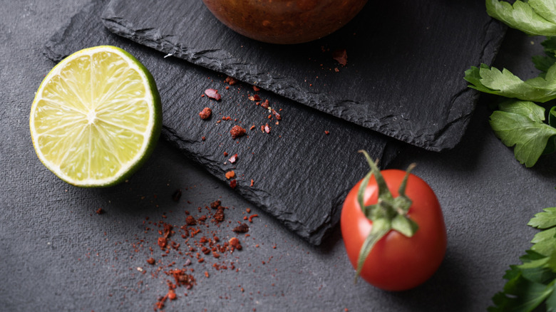 Harissa paste in a small glass jar with a wooden spoon, pictures with green chilis and a tomato