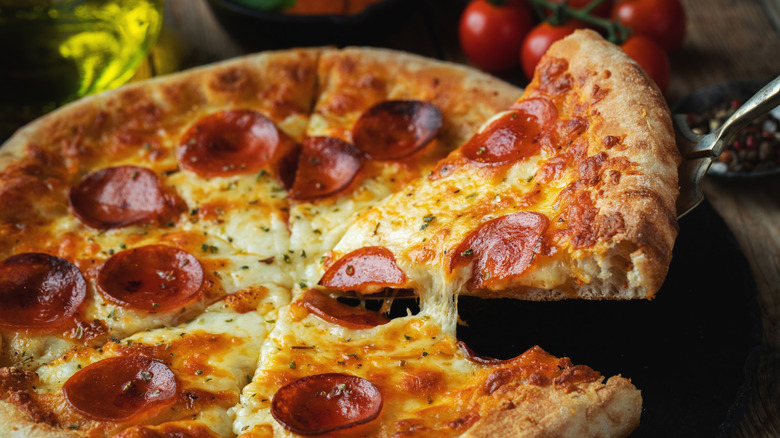 A homemade pepperoni pizza with a slice being pulled from it