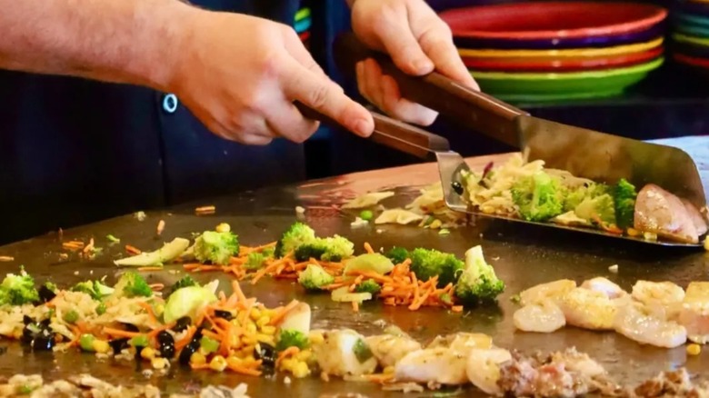 Fire + Ice worker cooking seafood and vegetables on the communal grill