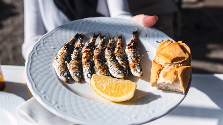 A plate of tiny grilled fish with lemon and crusty bread