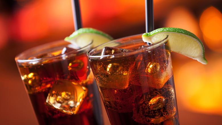 Two tall glasses of Long Island Iced Teas with lime slices on the rims