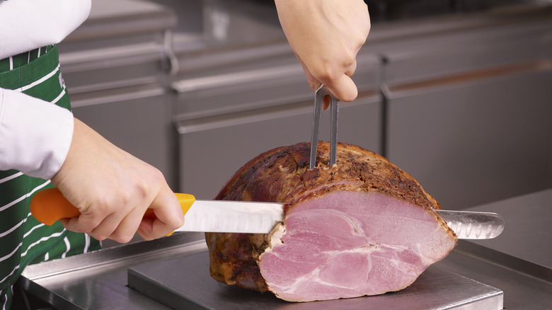 Close-up of a chef carving a ham