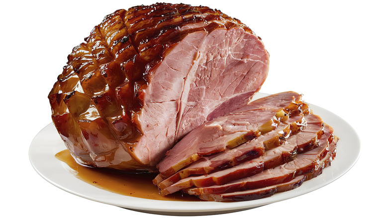 Scored ham covered in glaze against a white background