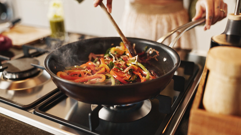 A wooden spoon stirring food on a stove