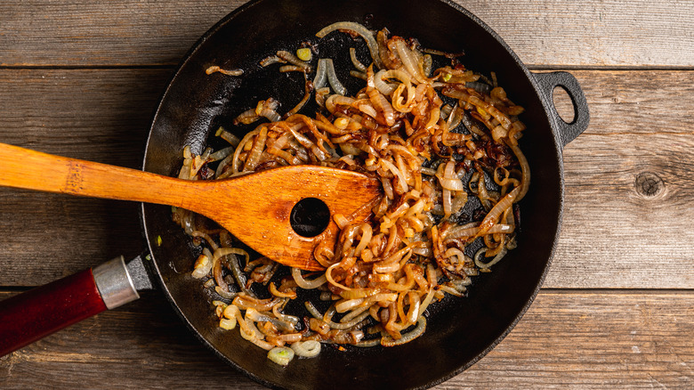 Caramelized onions in a cast iron pan with a wooden spatula