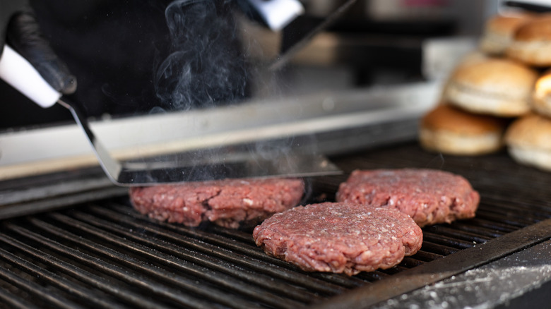 Burger patties on the grill seasoned with salt and pepper
