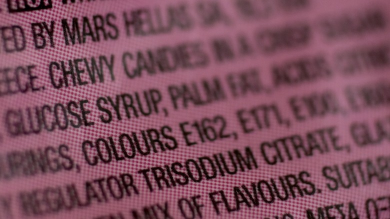 Food additives and E-numbers for color additives are pictured on a back of a package showing the ingredients