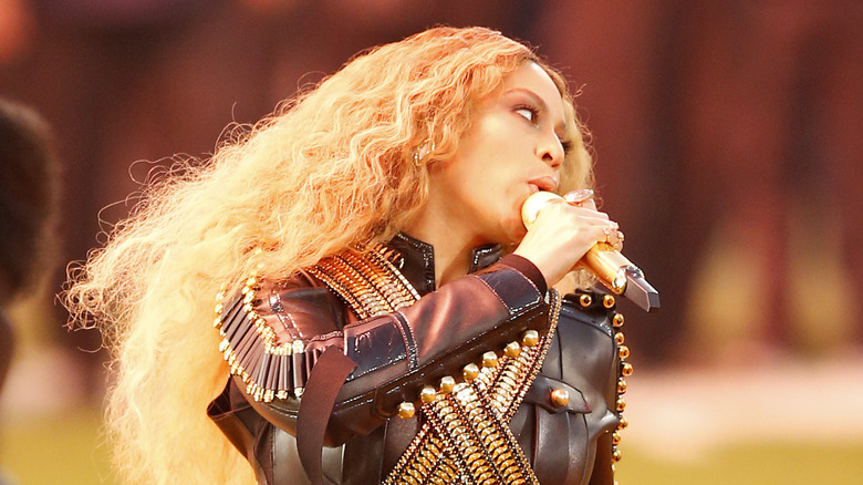Beyoncé performing in a black leather jacket with gold ornamentation.