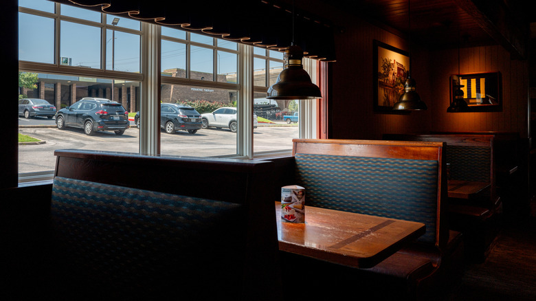 Empty booths in a dark, wood paneled dining room.