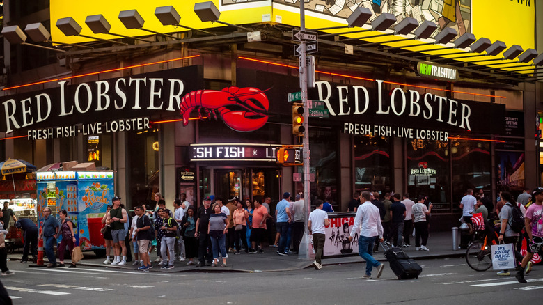 Crowds cross in front of a glass walled Red Lobster on Times Square.
