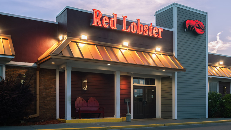 Neon Red Lobster sign lit above the entrance of a blue and white restaurant.