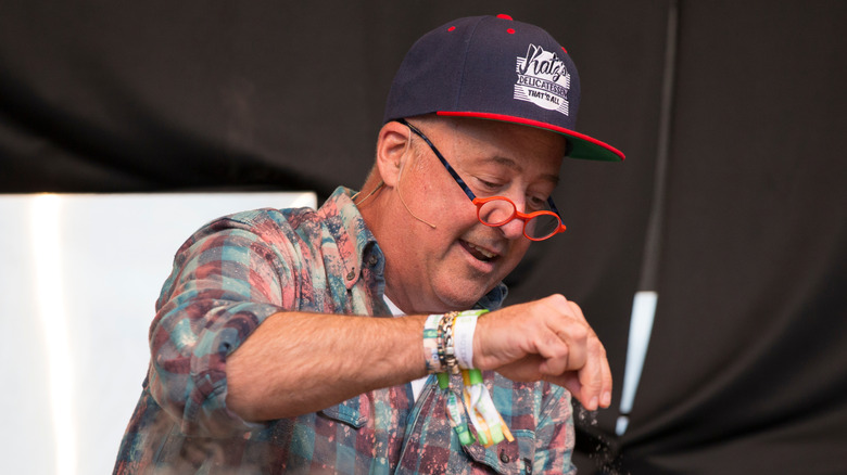 Andrew Zimmern seasons food at a cooking demonstration