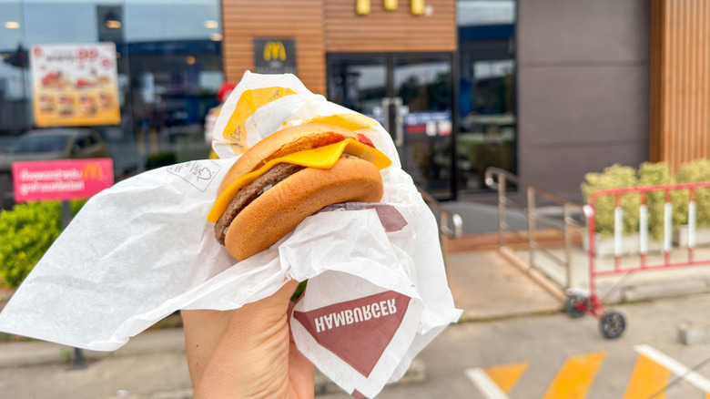 Hand holding a cheeseburger from McDonald's