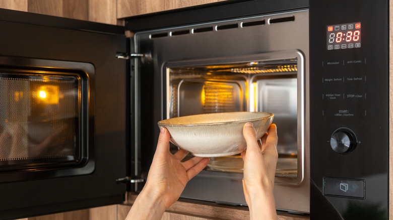 Hands putting bowl in microwave