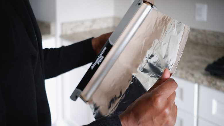 woman tearing off piece of aluminum foil