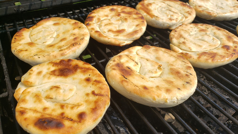 Several pieces of flatbread grilled golden-brown on grill grates