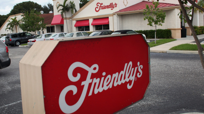 The exterior of a Friendly's restaurant with a sign and cars in the parking lot.