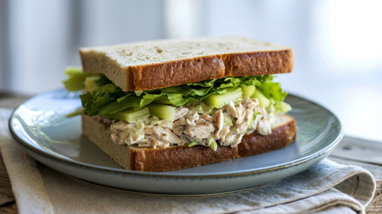 A closeup of a chicken salad sandwich on brown bread on a blue plate