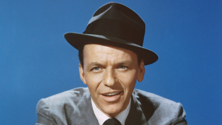 A color headshot of Frank Sinatra with a black fedora and gray suit