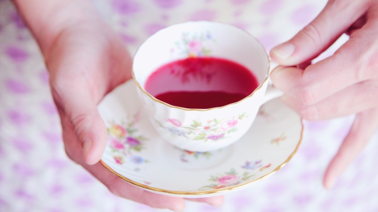 A woman holding a teacup with pinkie extended.