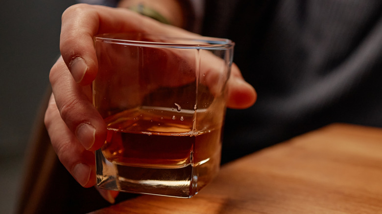 Hand holding a whiskey glass