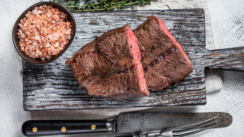 cooked flat iron steak cut in half with salt and herbs