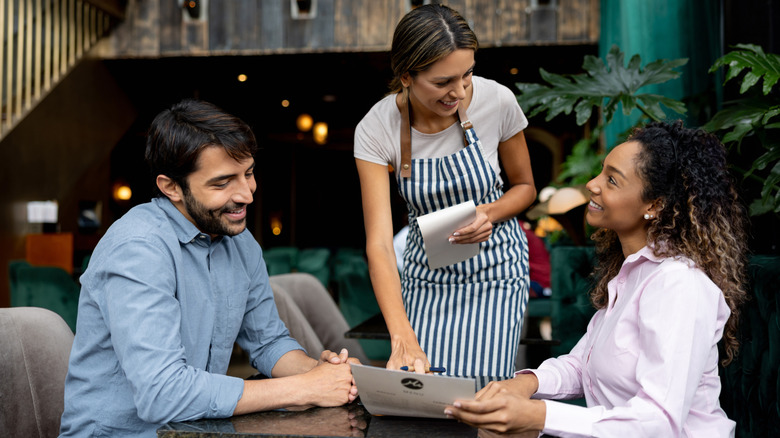 Restaurant server taking food order from two people at a table