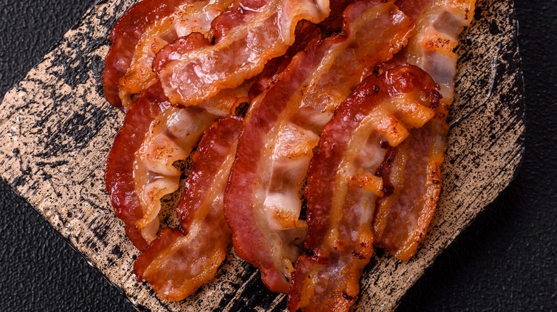 Strips of cooked bacon on a wood board