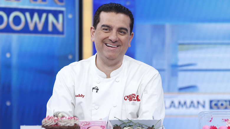 Buddy Valastro smiling in front of cupcakes
