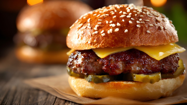 Cheeseburger with pickles and cheese on wooden surface